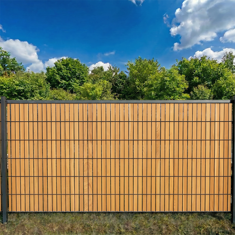 Lärche rustikal Sichtschutzstreifen im Doppelstabmattenzaun als Sichtschutz im Garten bei blauem Himmel und Bäumen.